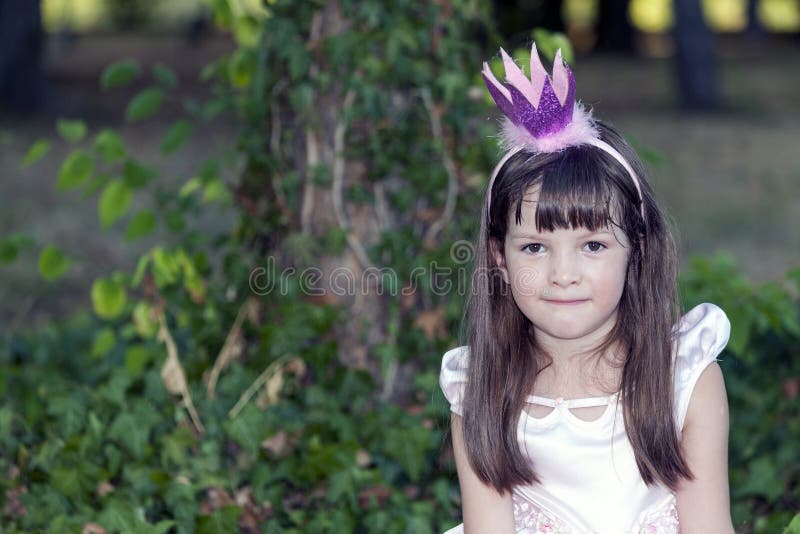 Chiuda sul ritratto di una bambina dolce con una corona sul suo hea immagine stock libera da diritti Chiuda sul ritratto di una bambina dolce con una corona sul suo hea immagine stock libera da diritti