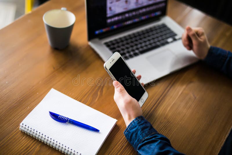 Chiuda sull'uomo a funzioni multiple delle mani che usando il wifi di collegamento del cellulare e del computer portatile immagine stock Chiuda sull'uomo a funzioni multiple delle mani che usando il wifi di collegamento del cellulare e del computer portatile immagine stock