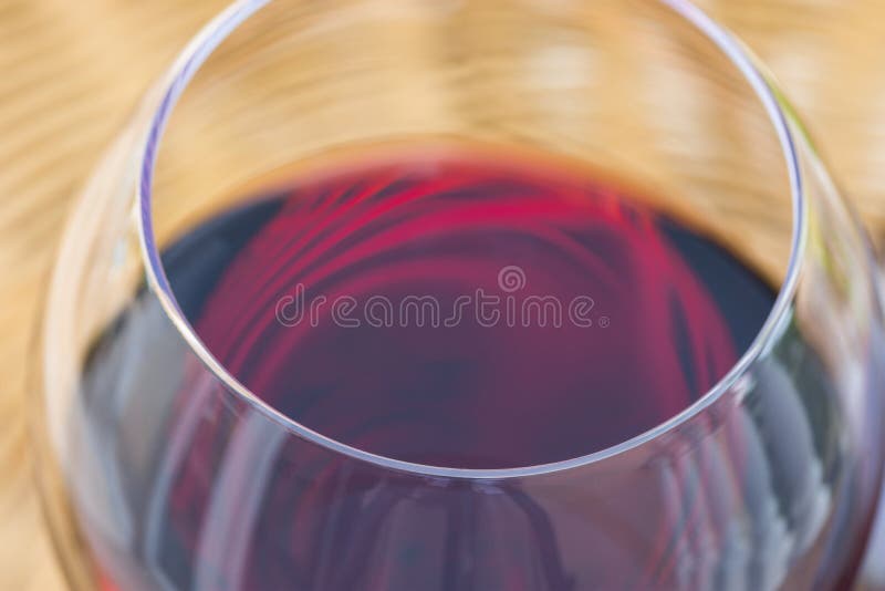 Chiuda sulla macro di vetro di vino rosso sulla Tabella di vimini del rattan nel terrazzo del giardino della villa o del palazzo immagini stock Chiuda sulla macro di vetro di vino rosso sulla Tabella di vimini del rattan nel terrazzo del giardino della villa o del palazzo immagini stock