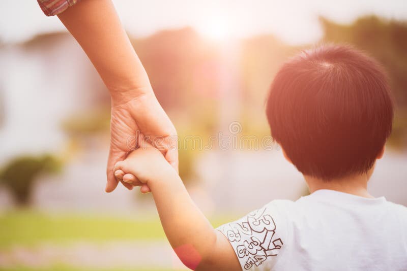 Chiuda sulla madre che tiene una mano del ` s del bambino fotografia stock Chiuda sulla madre che tiene una mano del ` s del bambino fotografia stock
