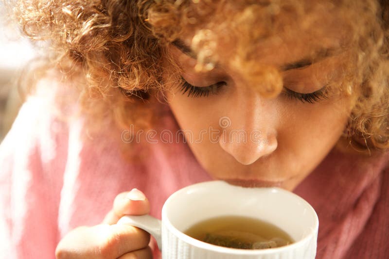 Chiuda sulla tazza bevente della giovane donna di colore di tè fotografie stock