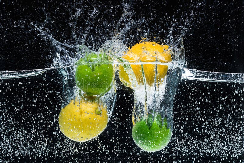 Chiuda sulla vista dei limoni e delle limette freschi in acqua immagine stock