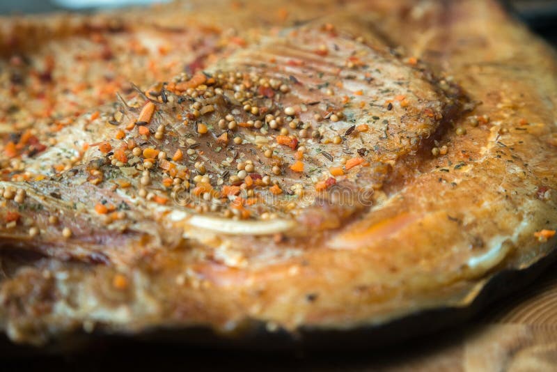 Chiuda sulla vista orizzontale dei filetti di pesce affumicati con condimento sul bordo servente di legno immagine stock Chiuda sulla vista orizzontale dei filetti di pesce affumicati con condimento sul bordo servente di legno immagine stock