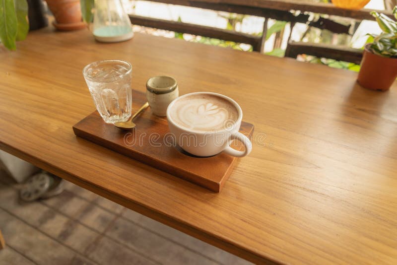 Chiudi di una tazza di caffè, di caffellatte o di un'espresso con tavoletta di legno al mattino per colazione o per pausa Vista d fotografia stock libera da diritti