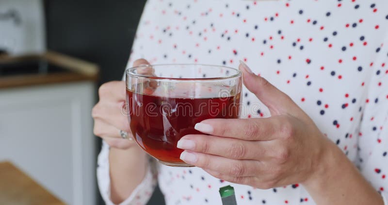 Chiudi la vista delle mani femminili che reggono la tazza con il tè caldo