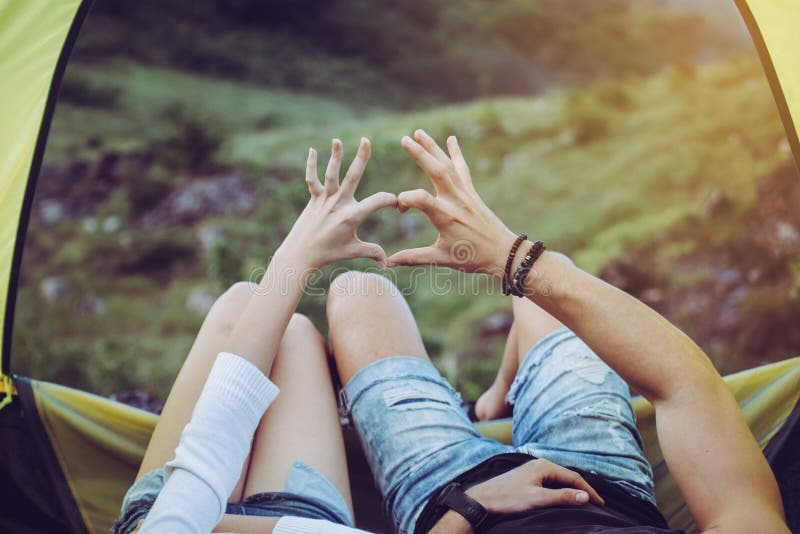 Chiudi le mani coppia amante che mostra la forma del cuore nella tenda insieme, godi il concetto di campeggio fotografie stock