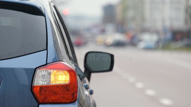 Chiusura della luce posteriore di un'auto rotta parcheggiata sul lato della strada della città con luci lampeggianti.