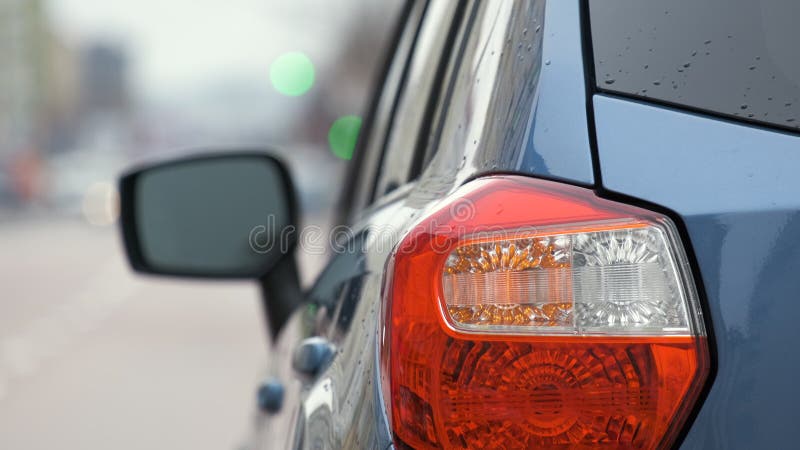 Chiusura della luce posteriore di un'auto rotta parcheggiata sul lato della strada della città con luci lampeggianti.