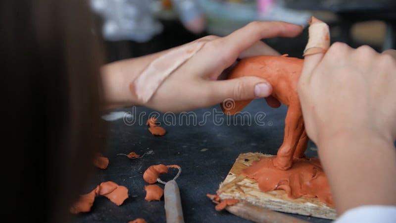 Chiusura delle mani dei bambini che scolpiscono un cavallo dall'argilla modellatrice.