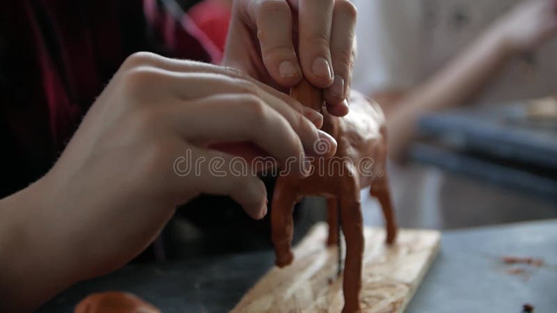 Chiusura delle mani dei bambini che scolpiscono un cavallo dalla modellazione dell'argilla in un laboratorio.