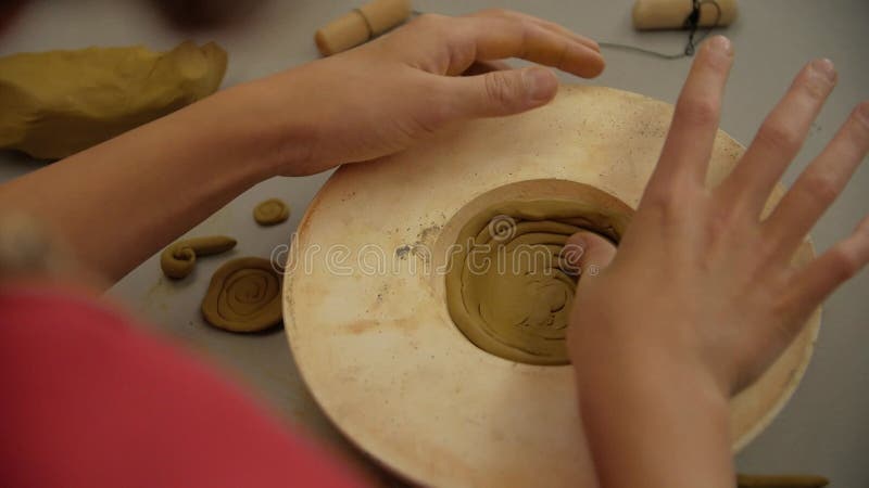 Chiusura delle mani dei bambini scolpendo l'argilla da modellazione in un laboratorio.