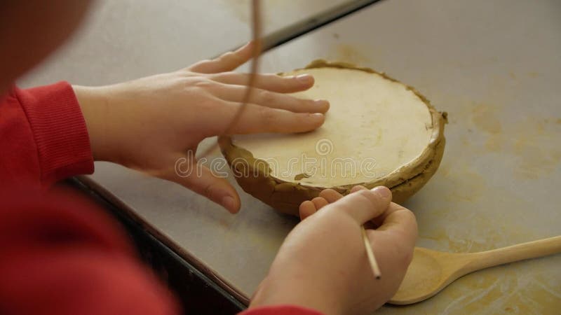 Chiusura delle mani dei bambini scolpendo l'argilla da modellazione in un laboratorio.