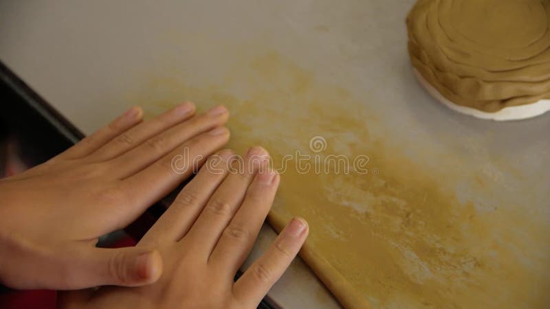 Chiusura di mani femminili sculacciate dall'argilla modellatrice in un laboratorio.