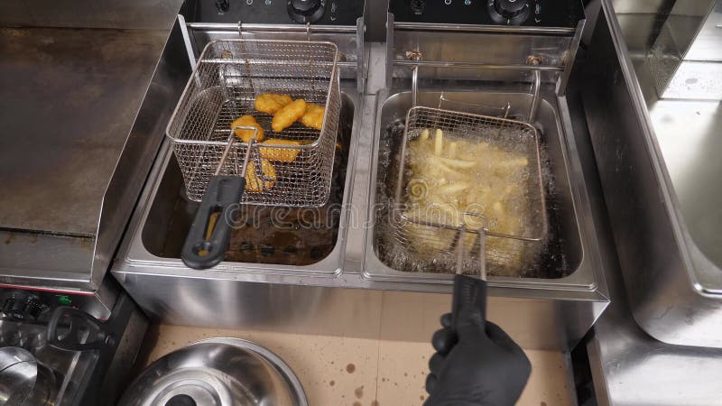 Chiusura di patatine fritte e pepite in un friggitrice con olio bollente. video d archivio