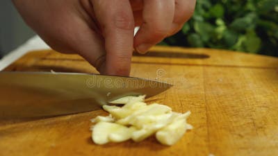 La mano del cuoco con un coltello affetta il pane su un tagliere da cucina
