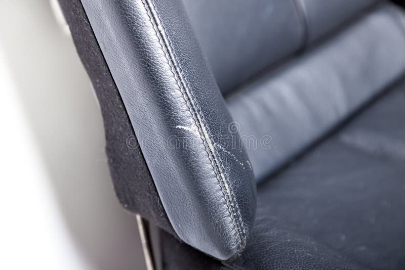 Chiusura di un difetto su una sedia a rotelle nera in pelle di colore bianco di vernice prima del restauro e della pulizia a secco