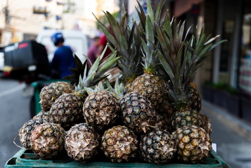 Chiusura di una pila di ananas freschi in una bancarella di mercato con fondo sfocato fotografie stock