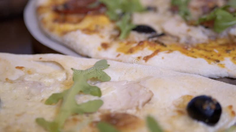 Chiusura di una pizza italiana cotta su un tavolo di legno in un caffè. slow motion 4k