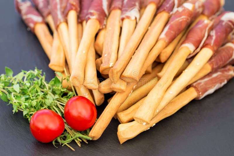Chlebowych kijów grissini z prosciutto baleronem na czarnej kamień desce Typowa włoska przekąska obrazy stock Chlebowych kijów grissini z prosciutto baleronem na czarnej kamień desce Typowa włoska przekąska obrazy stock