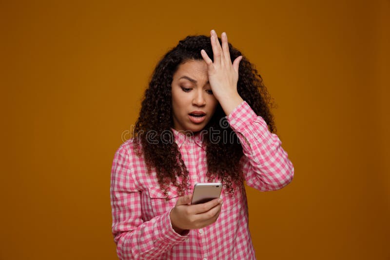 Chockad allvarlig kvinna som ser hennes mobiltelefon royaltyfri bild Chockad allvarlig kvinna som ser hennes mobiltelefon royaltyfri bild