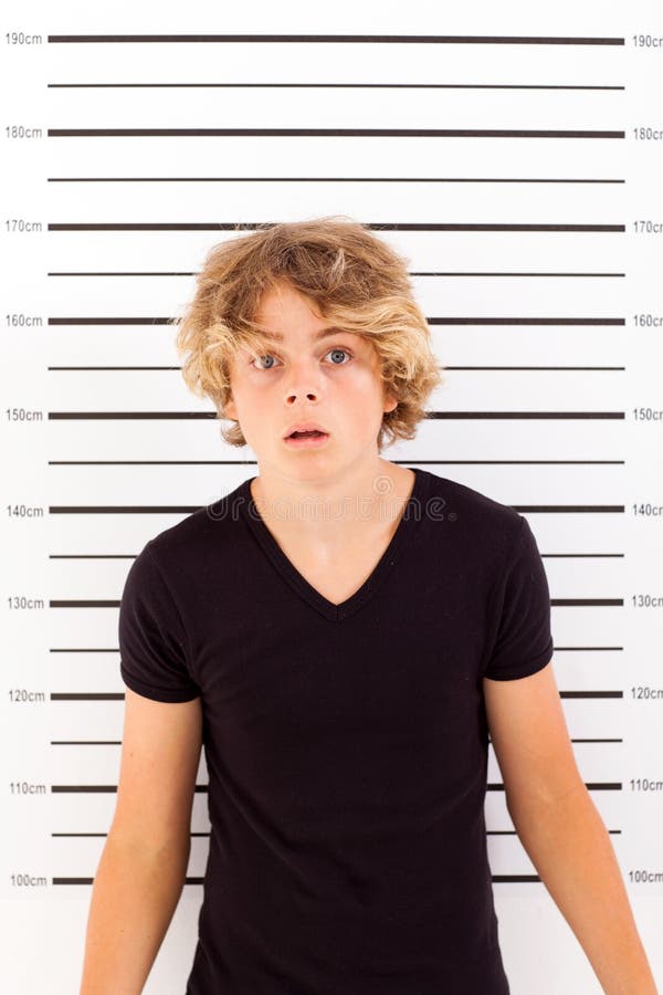 Shocked teen boy taking police mug shot. Shocked teen boy taking police mug shot