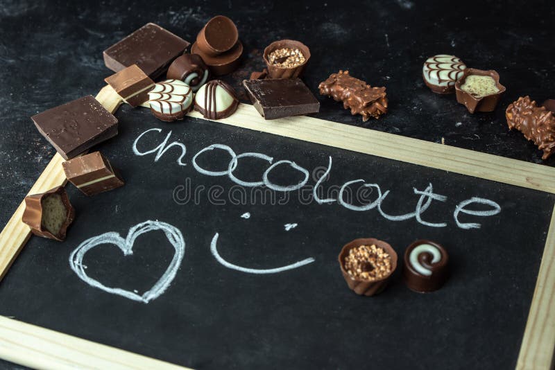Chocolat d'amour - différent, pralines douces de noir, lait et chocolat blanc sur un fond foncé et en bois image libre de droits Chocolat d'amour - différent, pralines douces de noir, lait et chocolat blanc sur un fond foncé et en bois image libre de droits