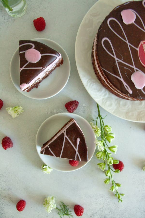 Chocolat de configuration et morceau de framboise de gâteau plats d'un plat blanc avec les fleurs blanches et les baies fraîches photographie stock libre de droits Chocolat de configuration et morceau de framboise de gâteau plats d'un plat blanc avec les fleurs blanches et les baies fraîches photographie stock libre de droits