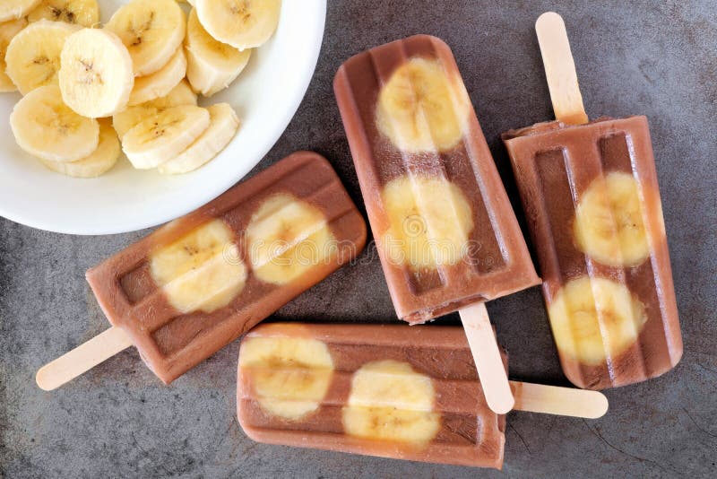 Chocolate banana popsicles on rustic grey background stock photo