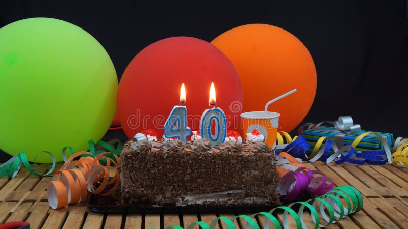 Chocolate birthday 40 cake with candles burning on rustic wooden table with background of colorful balloons stock photos Chocolate birthday 40 cake with candles burning on rustic wooden table with background of colorful balloons stock photos