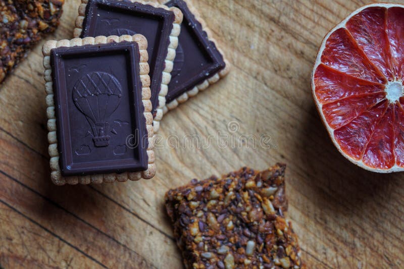 Chocolate Biscuits, Cereal Bar and Grapefruit on a Wooden Chopper Stock
