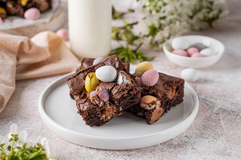 Chocolate brownie with Easter candies in the form of colored eggs with a bottle of milk. Easter dessert. Copy space