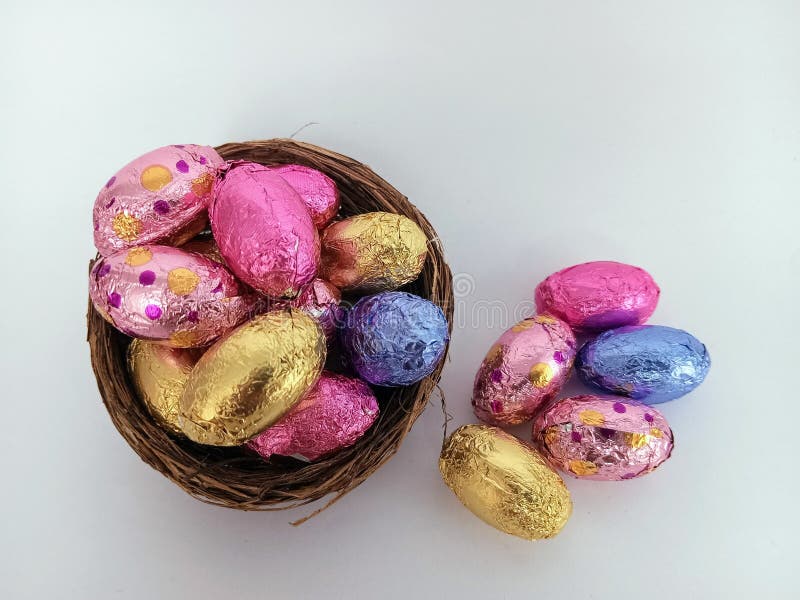 Chocolate Candy Easter Eggs Overflowing a Twig Birds Nest on a White