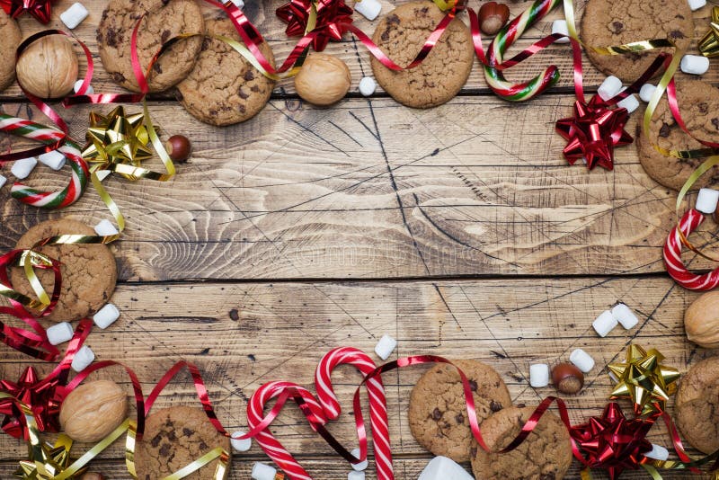 Chocolate chip cookies Christmas canes caramel red gold scenery and marshmallow on wooden background. Copy space Frame royalty free stock image Chocolate chip cookies Christmas canes caramel red gold scenery and marshmallow on wooden background. Copy space Frame royalty free stock image