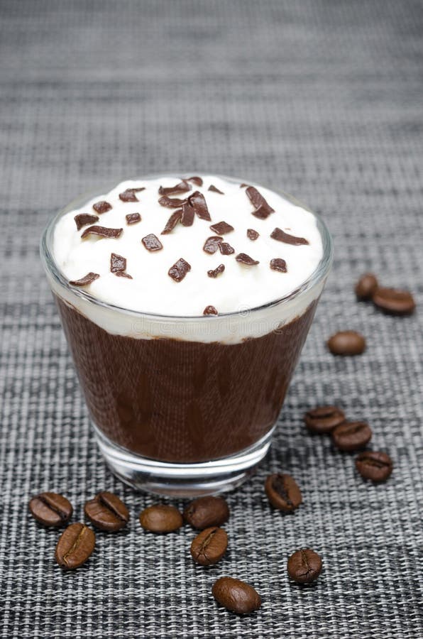 Chocolate-coffee mousse with whipped cream in a glass on gray