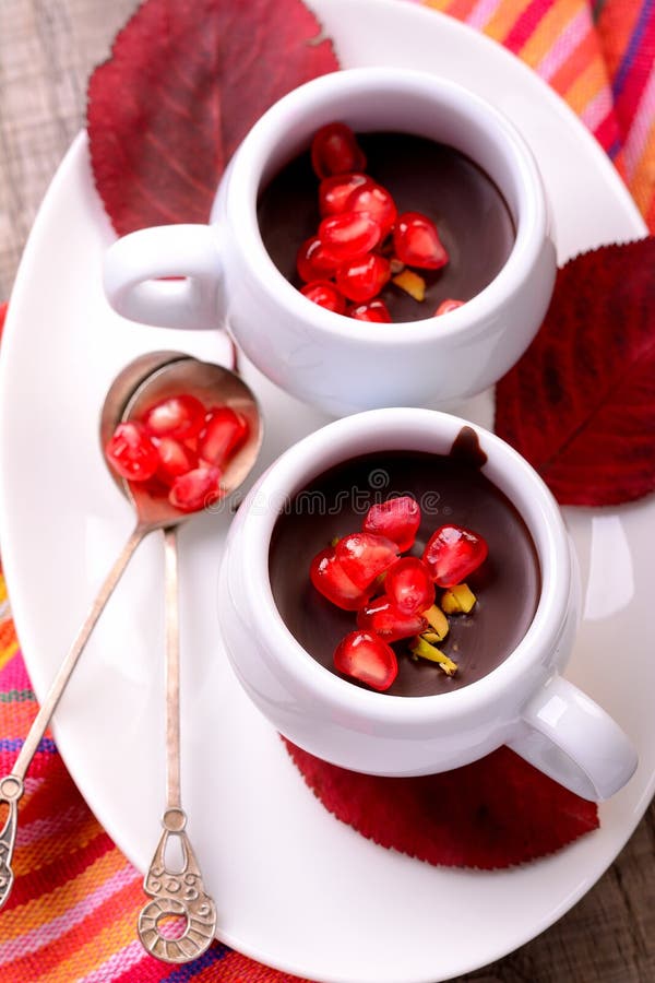 Chocolate cream with pomegranate seeds on a wooden