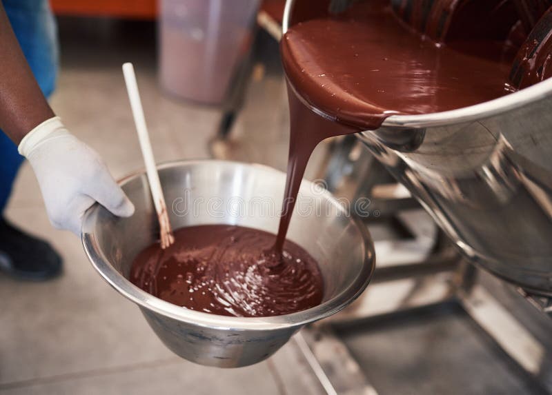 Chocolate derretido que vierte en un cuenco en fábrica de la confitería foto de archivo Chocolate derretido que vierte en un cuenco en fábrica de la confitería foto de archivo