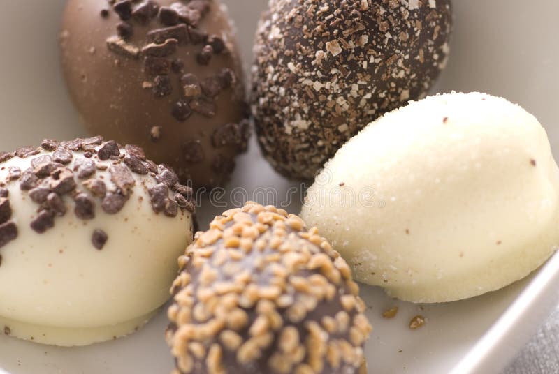 Una vista ravvicinata di cinque diverse uova di pasqua fatta di cioccolato fondente o bianco con vari tipi di dado e cospargere di condimenti.