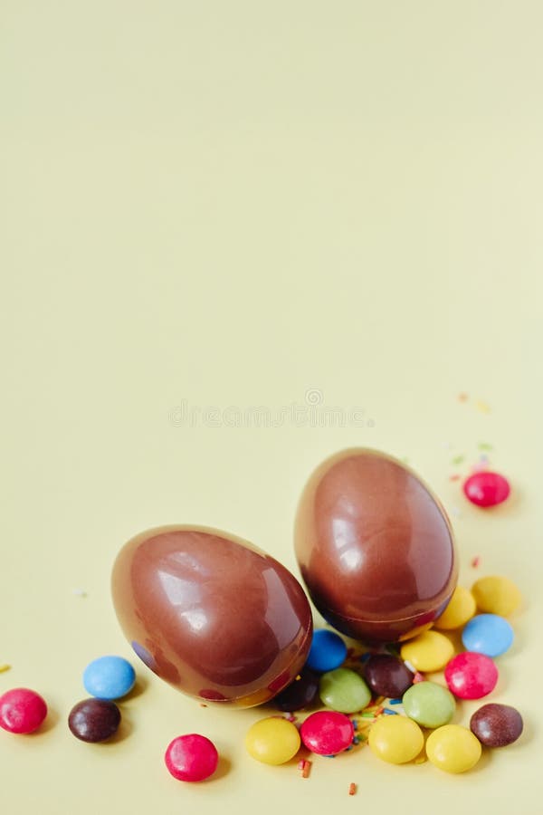 Chocolate Easter Eggs And Sweets On Pastel Yellow Background Stock