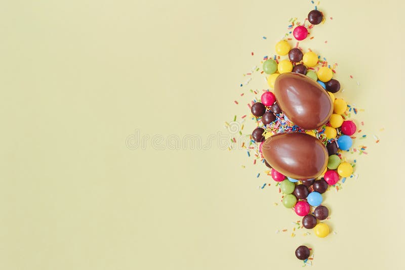 Chocolate Easter Eggs And Sweets On Pastel Yellow Background Stock