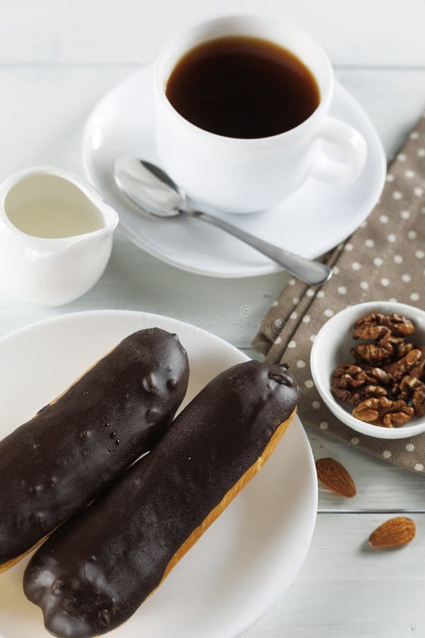 Chocolate Eclairs with Coffee and Milk. Traditional Sweet Breakfast