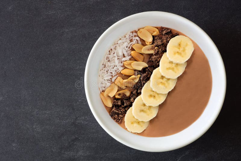 Chocolate, manteca de cacahuete, plátano, cuenco del smoothie en pizarra imagen de archivo libre de regalías Chocolate, manteca de cacahuete, plátano, cuenco del smoothie en pizarra imagen de archivo libre de regalías