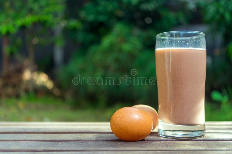 Chocolate Milk and Eggs on Wooden Ground on Green Background Stock