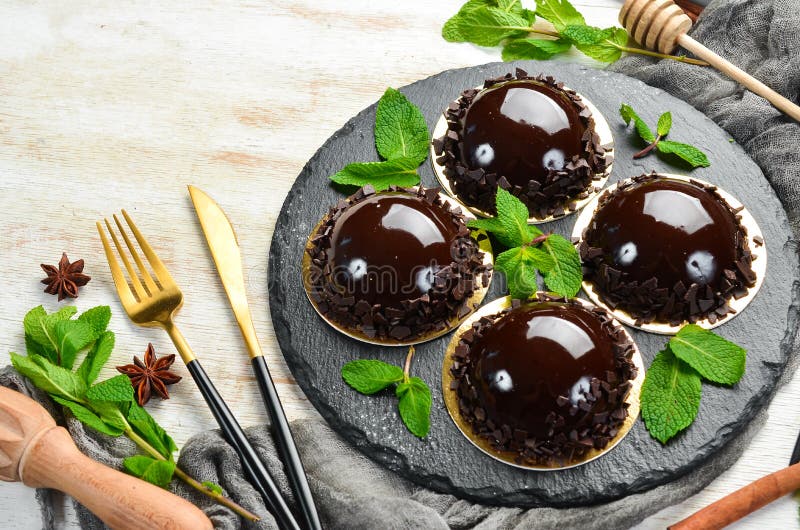 Chocolatemousse Dessert `Opera` on a Black Plate with Mint. Top View