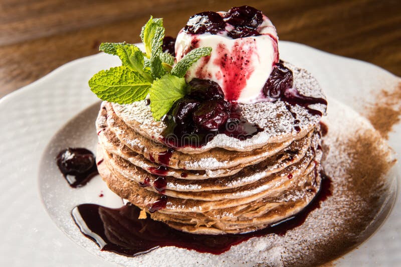 Chocolate Pancakes with Vanilla Ice Cream and Warm Cherry Sauce on white plate