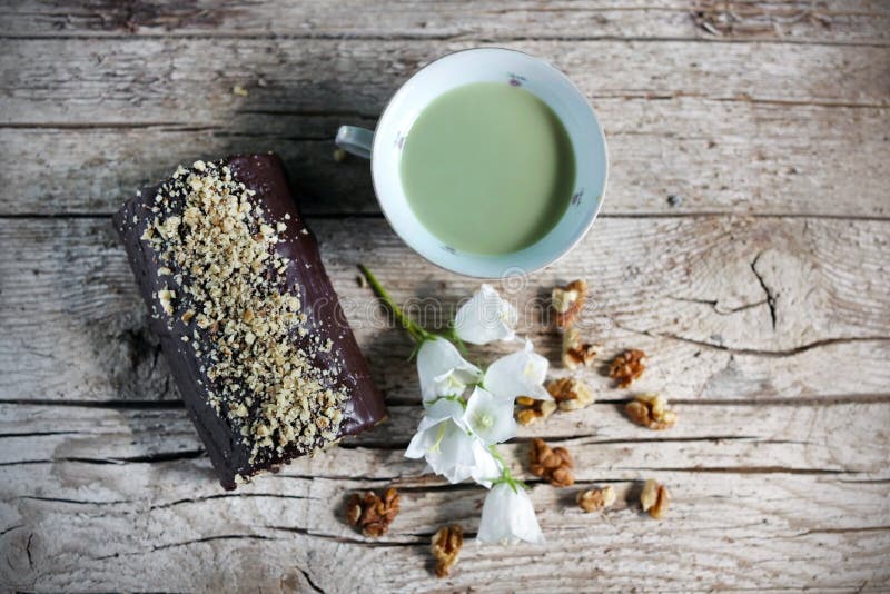 Chocolate swiss roll with walnuts and cup of green tea royalty free stock photography