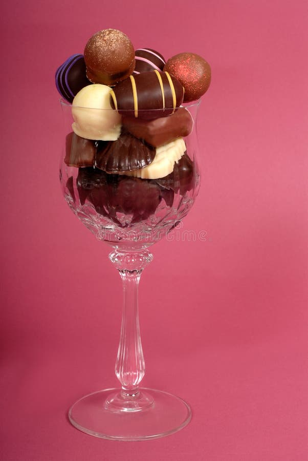 Vertical view of delicious dark and semi-sweet chocolates in a cut crystal wine glass. Vertical view of delicious dark and semi-sweet chocolates in a cut crystal wine glass