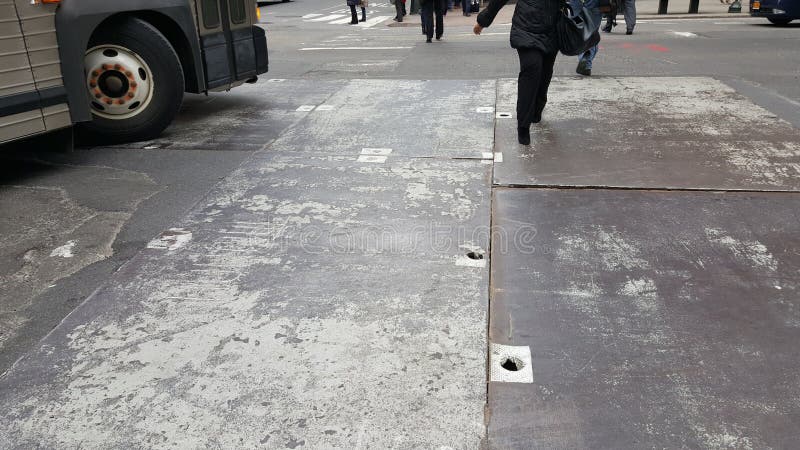Chodzić przez miastową ulicę z autobusowymi kręcenia i metalu hihole ulicznymi pokrywami zdjęcia stock Chodzić przez miastową ulicę z autobusowymi kręcenia i metalu hihole ulicznymi pokrywami zdjęcia stock