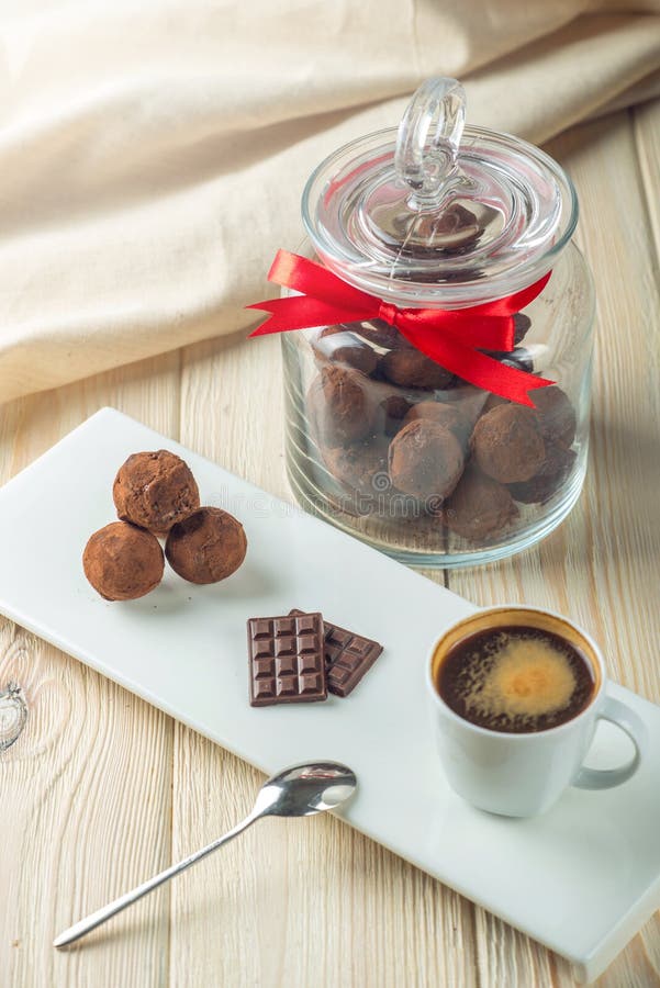 Choklad klumpa ihop sig tryfflar på ett tefat bredvid en krus av godisen och en kopp kaffe Begreppet av läckra efterrättgåvor royaltyfri fotografi Choklad klumpa ihop sig tryfflar på ett tefat bredvid en krus av godisen och en kopp kaffe Begreppet av läckra efterrättgåvor royaltyfri fotografi