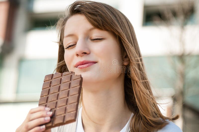 Portrait of young beautiful woman eating chocolate - lifestyle outdoor image. Portrait of young beautiful woman eating chocolate - lifestyle outdoor image