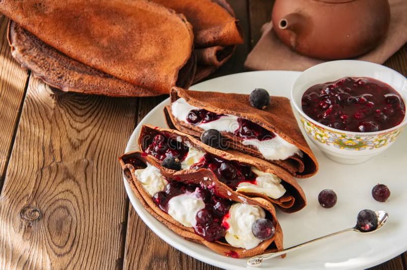 Chokladkräppblinis med sauc för gräddfil och för svart vinbär royaltyfria bilder Chokladkräppblinis med sauc för gräddfil och för svart vinbär royaltyfria bilder